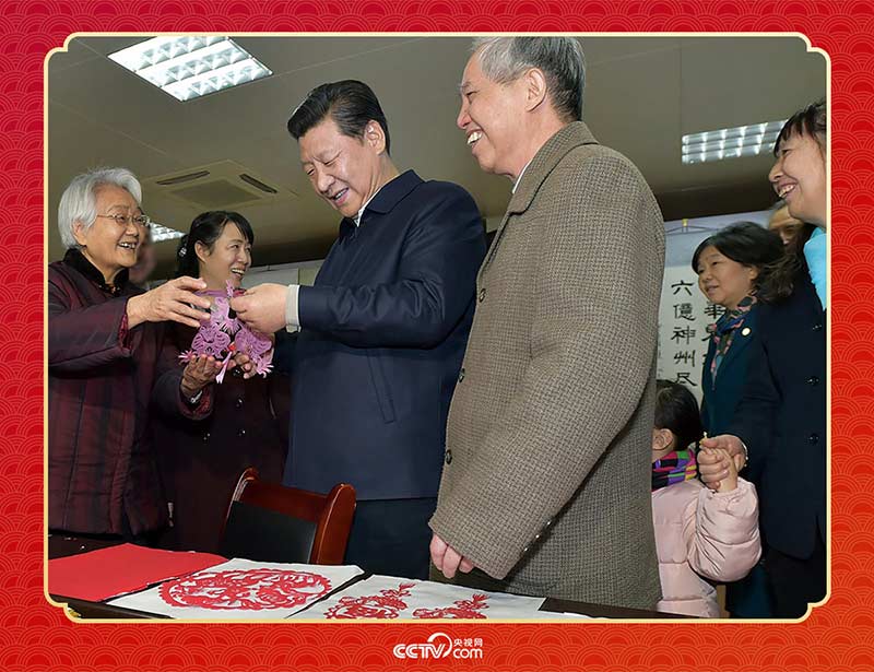 2015年2月15日,习近平在西安市雁塔区电子城街道二〇五所社区服务中心欣赏社区居民的剪纸作品。